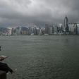 A man reads a newspaper on the edge of a promenade overlooking Victoria Harbour in Hong Kong