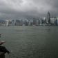 A man reads a newspaper on the edge of a promenade overlooking Victoria Harbour in Hong Kong