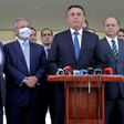 Brazilian President Jair Bolsonaro (C) speaks alongside Brazilian Economy Minister Paulo Guedes (L), deputies and senators during a statement on financial aid for vulnerable Brazilians amid the COVID-19 pandemic, at Planalto Palace, in Brasilia