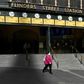 A woman walks out of a near-deserted Flinders Street Station in Melbourne after the state announced new restrictions to contain coronavirus
