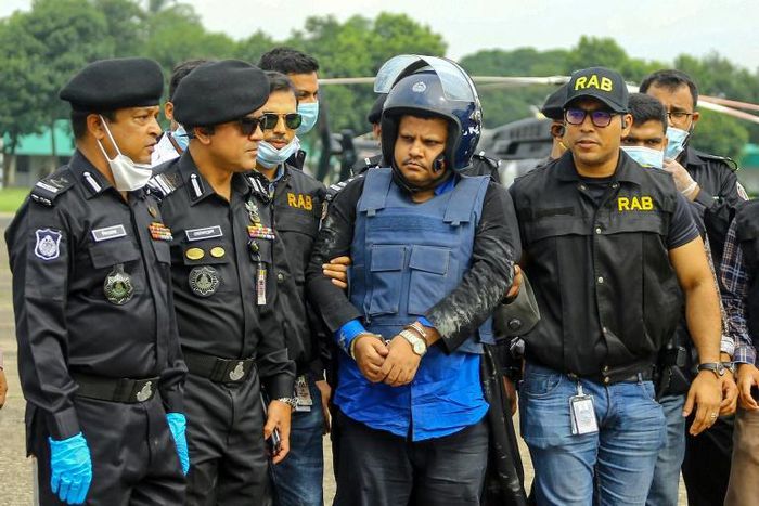Anti-crime unit personnel escort Bangladeshi hospital owner Mohammad Shahed (C), who was arrested on suspicion of distributing fake certificates saying patients had tested negative for COVID-19