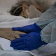 Dr Moyra Lopez holds the hand of a terminally ill patient at the Barros Luco hospital ward in Santiago where loved ones are able to see dying patients even if they have contracted the coronavirus
