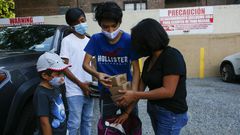 Maria, a domestic worker from Mexico, and her children receive food donations at a distribution center in Corona, Queens