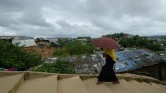 A Rohingya woman climbs a hill as she goes back to her makeshift home in Jamtoli refugee camp, near Ukhia in Bangladesh