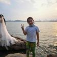 A girl gestures while a couple poses for a wedding photographer next to East Lake in Wuhan