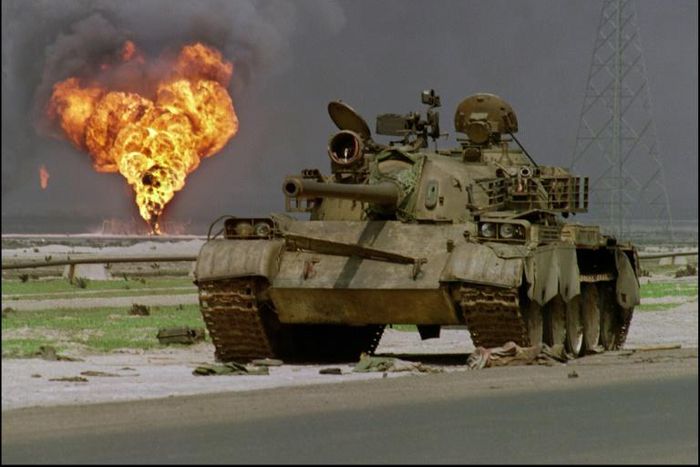 An abandoned Iraqi Soviet-made T-62 tank sits in the Kuwaiti desert as an oil well burns in the background, on April 2, 1991