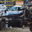 Police officers in Personal Protective Equipment (PPE) investigate around the police cars destroyed by a bomb explosion in front of Central Police Station in Kampala, Uganda, on November 16, 2021. - Two explosions hit Uganda's capital Kampala on Novemb...