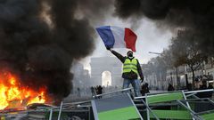 A demonstrator waves the French flag on a burning barricade on Paris’s Champs-Élysées avenue during a demonstration against the raising of fuel taxes on Novermber 24, 2018. Michel Euler/AP