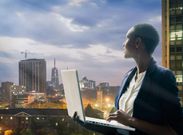 Businesswoman holding her laptop by the Nairobi city skyline