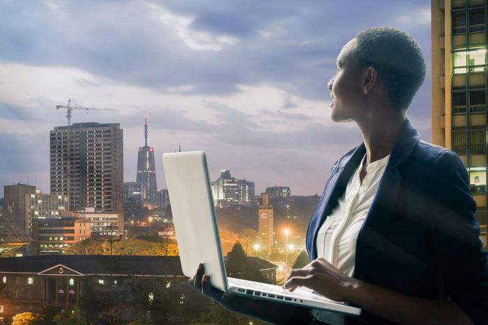 Businesswoman holding her laptop by the Nairobi city skyline