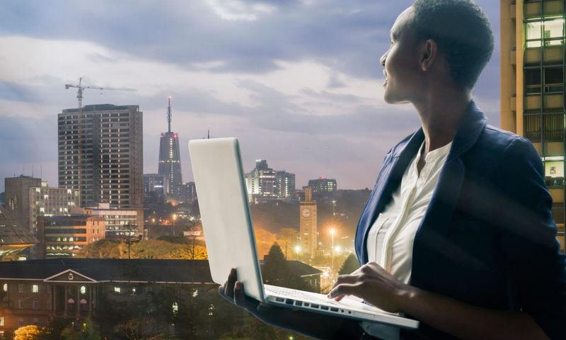 Businesswoman holding her laptop by the Nairobi city skyline