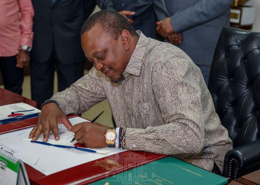 President Uhuru Kenyatta signing a document in his office