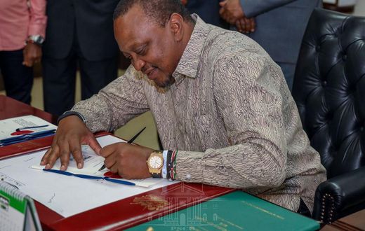 President Uhuru Kenyatta signing a document in his office