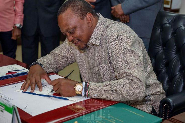 President Uhuru Kenyatta signing a document in his office
