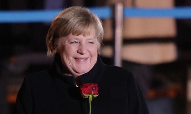 Outgoing German chancellor Angela Merkel holds a red rose at the conclusion of her military tattoo ceremony hosted by the Bundeswehr on 2 December. Photograph: Sean Gallup/Getty Images