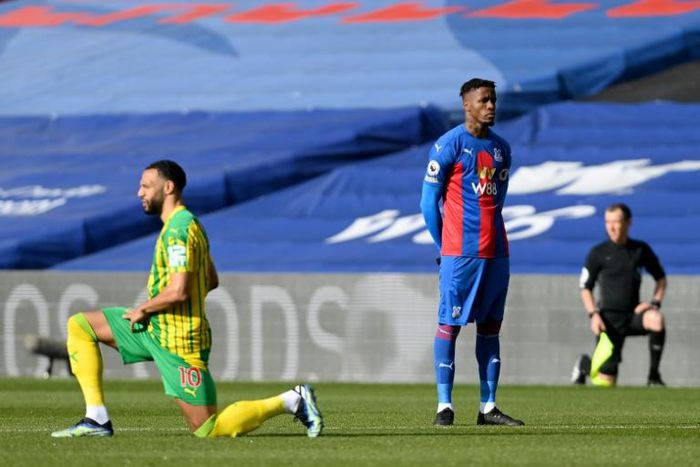 Crystal Palace's Wilfried Zaha stands as players take the knee