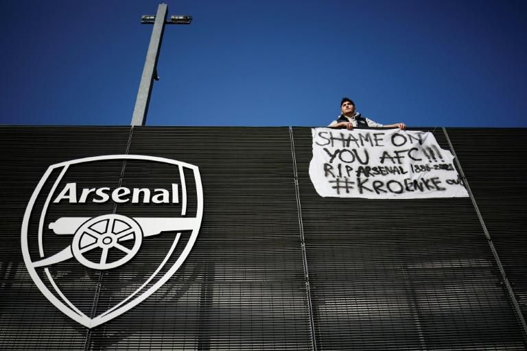 An Arsenal fan hangs a banner aimed at the club's America owner on their Emirates Stadium