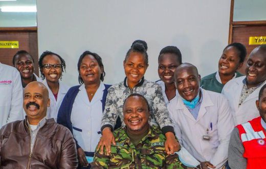 President Uhuru Kenyatta (in camouflage jacket) poses for a photo with health staff in one of the facilities