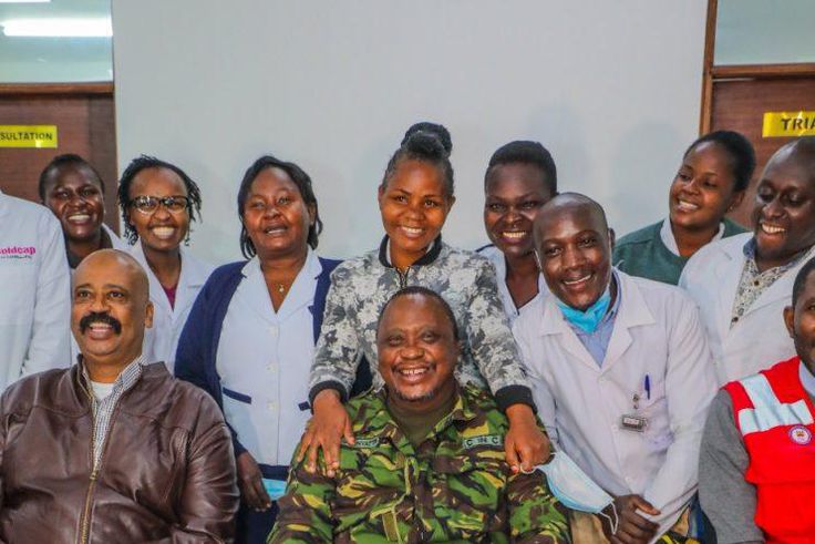 President Uhuru Kenyatta (in camouflage jacket) poses for a photo with health staff in one of the facilities