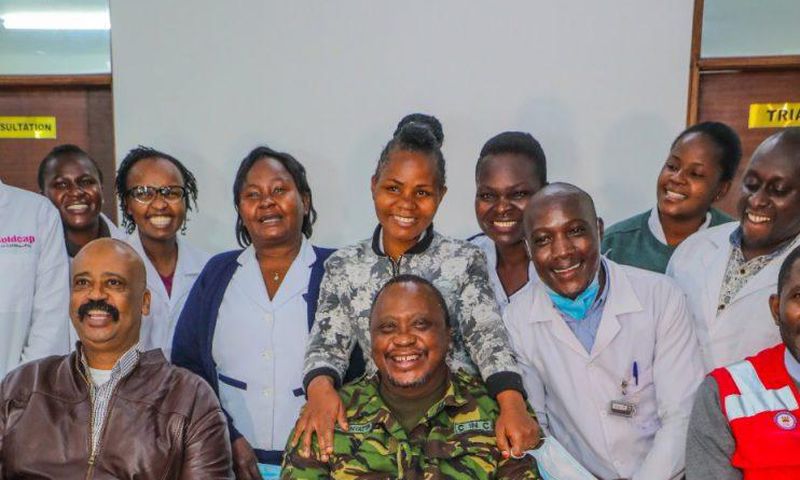 President Uhuru Kenyatta (in camouflage jacket) poses for a photo with health staff in one of the facilities