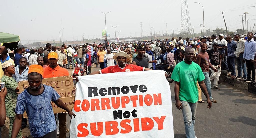People hold a banner as they protest against hiked in pump price by the government during a worker's rally at Gani Fawehinmi Partk, Ojota district in Lagos on January 13, 2012. The government and Labour are scheduled to meet again tomorrow to resolve the stalement at yesterday's meeting in order to put an end to on-going strike following government scrapping of fuel subsidy. AFP PHOTO/ PIUS UTOMI EKPEI (Photo credit should read PIUS UTOMI EKPEI/AFP via Getty Images)