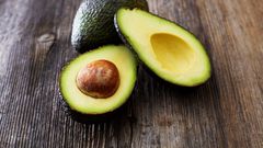 Whole and sliced avocado on wood