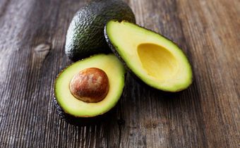 Whole and sliced avocado on wood