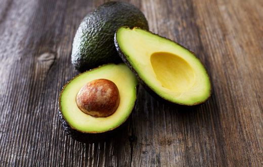 Whole and sliced avocado on wood