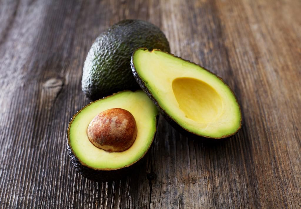 Whole and sliced avocado on a chopping board