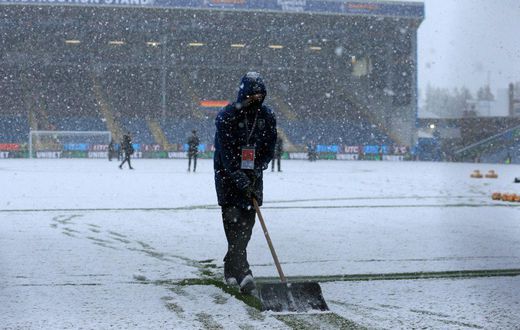 Groundstaff clear snow at Burnley's Turf Moor ground