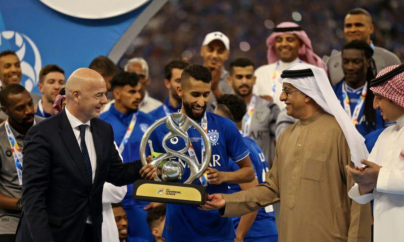 FIFA President Gianni Infantino (left) presents the trophy to Al Hilal midfielder Salman Al-Faraj