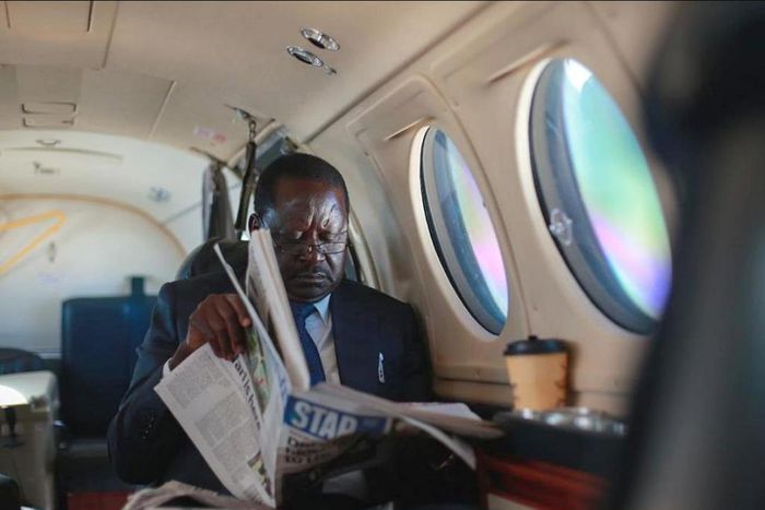 ODM leader Raila Odinga reading a newspaper in a plane