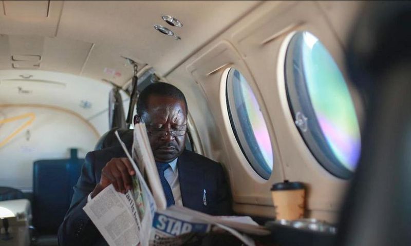 ODM leader Raila Odinga reading a newspaper in a plane