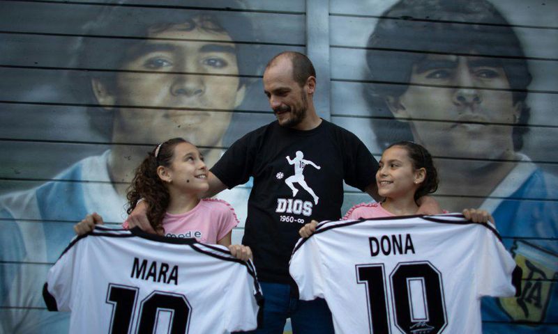 Walter Rotundo, a huge fan of the late Diego Maradona, poses with his daughters Mara (L) and Dona (R)