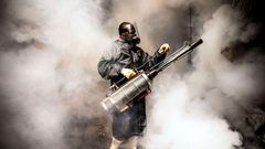 TOPSHOT - A member of a privately-funded NGO working with county officials wearing protective gear fumigates and disinfects on April 15, 2020, during the dusk-to-dawn curfew imposed by the Kenyan Government, the streets and the stalls at Parklands City...