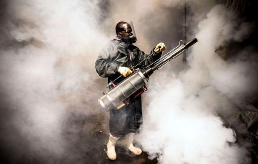 TOPSHOT - A member of a privately-funded NGO working with county officials wearing protective gear fumigates and disinfects on April 15, 2020, during the dusk-to-dawn curfew imposed by the Kenyan Government, the streets and the stalls at Parklands City...