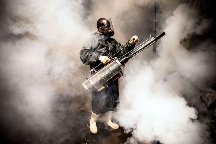 TOPSHOT - A member of a privately-funded NGO working with county officials wearing protective gear fumigates and disinfects on April 15, 2020, during the dusk-to-dawn curfew imposed by the Kenyan Government, the streets and the stalls at Parklands City...