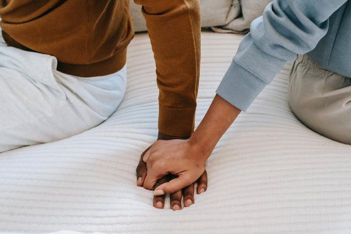 Couple holding hands on bed [Image: Alex Green]