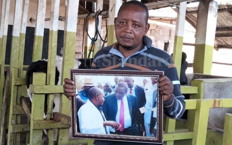 John Njoroge holding a picture he took with President Uhuru Kenyatta