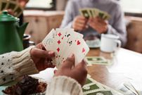 Hands of woman holding cards while playing with friends in camper van