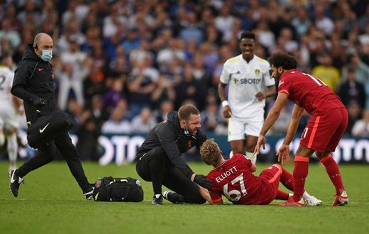 A trainer runs on the pitch to help Liverpool's Harvey Elliott (C)