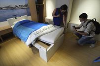 Journalists look at cardboard beds for the Tokyo 2020 Olympic and Paralympic at the Village Plaza near Tokyo 2020 Olympic and Paralympic Village Sunday, June 20, in Tokyo.EUGENE HOSHIKO / AP