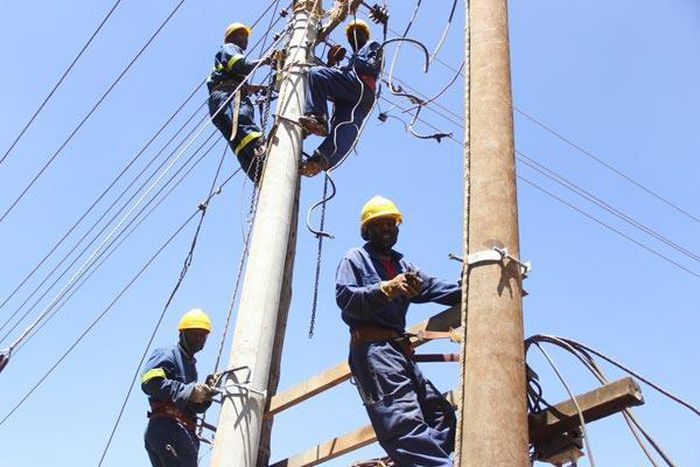Kenya Power workers install concrete pole
