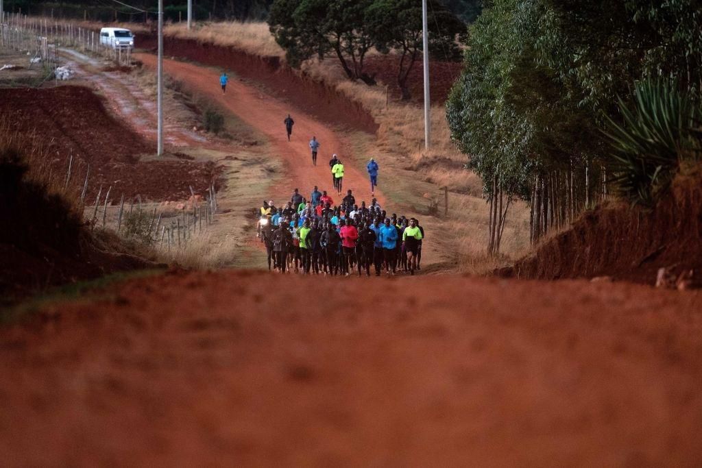 A group of runners takes part a training session on March 13, 2019 in Iten, Kenya. - As dawn breaks high in Kenya's Rift Valley, car headlights pick out groups of elite athletes, mere silhouettes on roadsides as their grinding daily training routine ge...