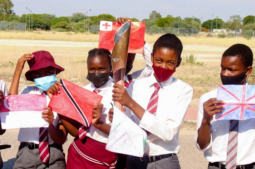 Schoolchildren in Mozambique holding the Baton and the flags of the Commonwealth
