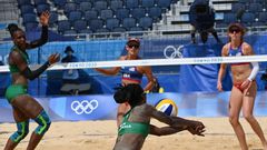 Kenya's Brackcides Khadambi (L), USA's Sarah Sponcil (back C) and USA's Kelly Claes (R) watch as Kenya's Gaudencia Makokha dives for the ball in their women's preliminary beach volleyball pool D match between the USA and Kenya during the Tokyo 2020 Olympic Games at Shiokaze Park in Tokyo on July 29, 2021. (Photo by Yuri CORTEZ / AFP) (Photo by YURI CORTEZ/AFP via Getty Images)