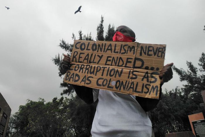 Protester holding placard in Nairobi which reads: "Colonialism never really ended. Corruption is as bad as colonialism."