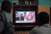 Somali men watch the news on September 6, 2014 in Mogadishu on a television set where is broadcasted a portrait of Somalia's Al-Qaeda-linked Shebab slain leader Ahmed Abdi Godane, recently killed in a US air strike. Somalia's Al-Qaeda-linked Shebab militants on September 6 announced the appointment of Godane's successor naming Ahmad Umar Abu Ubaidah, described by Shebab sources as a close lieutenant to Godane -- although the name is seen as likely to be a pseudonym. The group also vowed to avenge the death of Godane and said they would continue their fight to topple the country's internationally-backed government. AFP PHOTO / MOHAMED ABDIWAHAB (Photo credit should read Mohamed Abdiwahab/AFP via Getty Images)