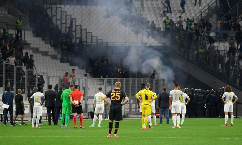 Flare for trouble: Players stand on the pitch as the match between Marseille and Galatasaray as held up