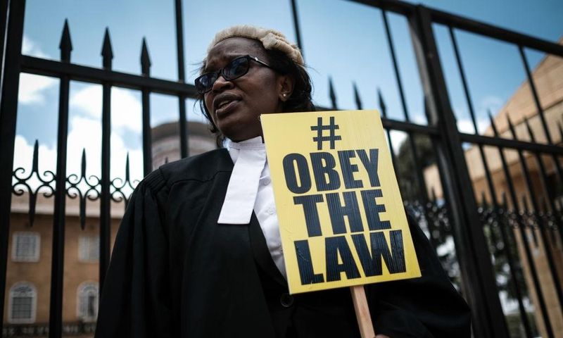 Kenyan lawyer and Law Society of Kenya's CEO Mercy Wambua holds a placard in front of the Supreme Court in Nairobi, on February 15, 2018 during a demonstration against impunity and disobedience of court orders. Kenya's Chief Justice on February 7 criti...